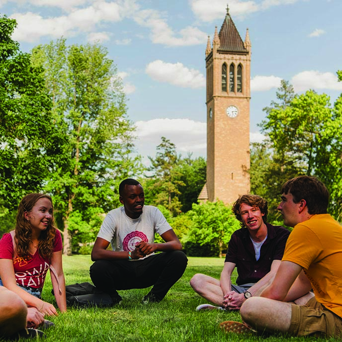 Four students talk as they study together seated at a table.