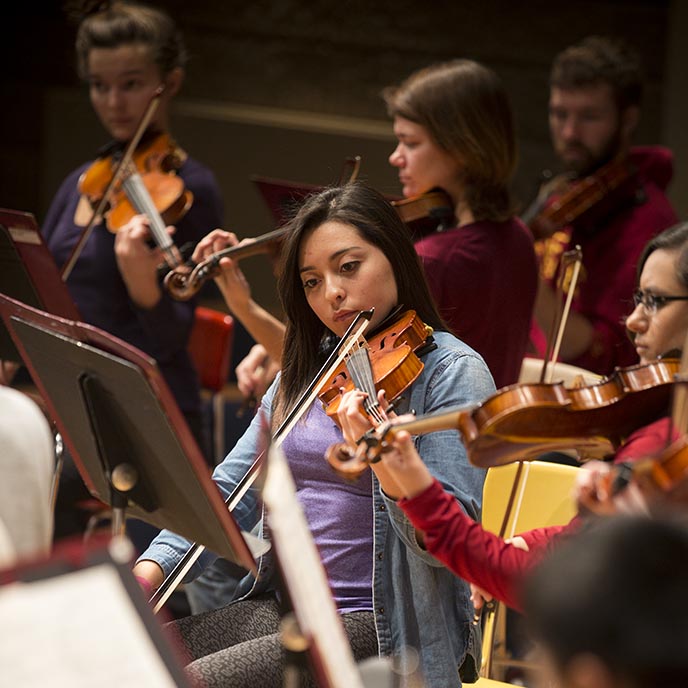 Closeup of a violinist during a group practice session.