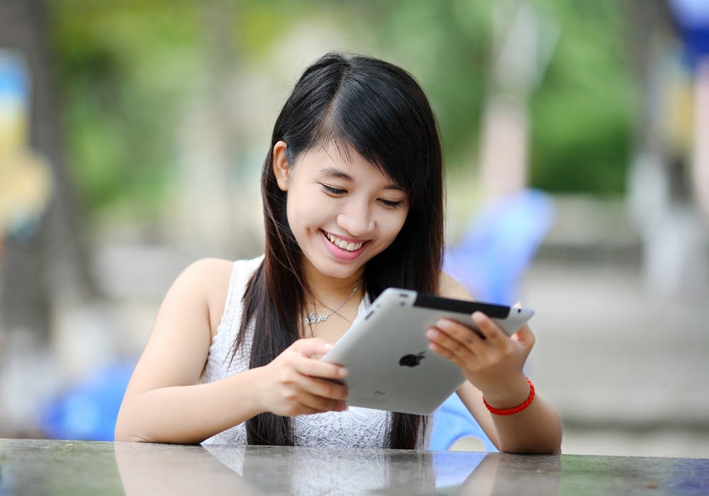 Student smiling at what they see on an iPad
